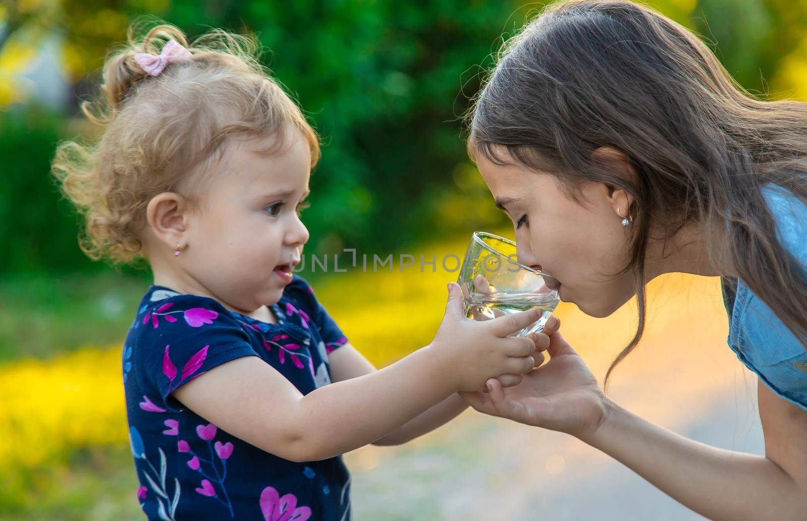 The child drinks water from a glass. Selective focus. Kid.