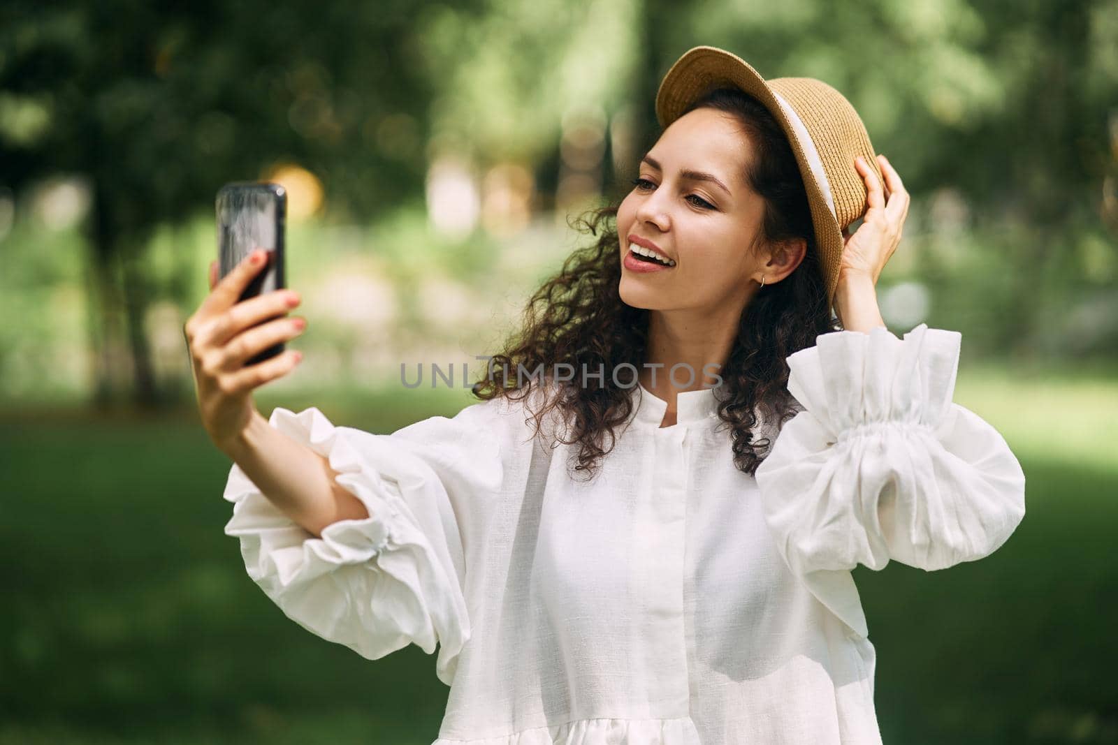 Young beautiful girl in a hat makes a selfie on her phone in the park. High quality photo