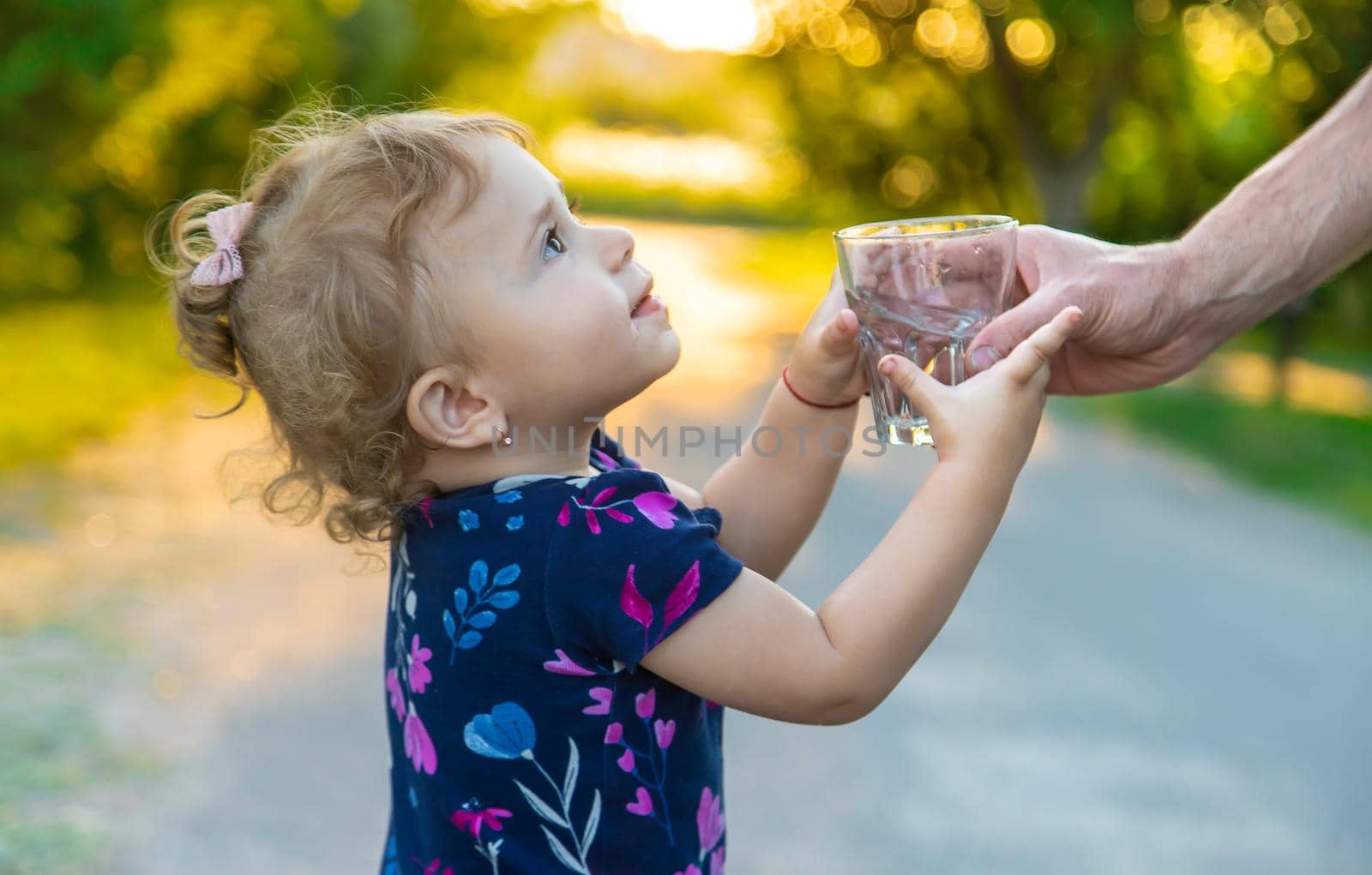 The child drinks water from a glass. Selective focus. Kid.