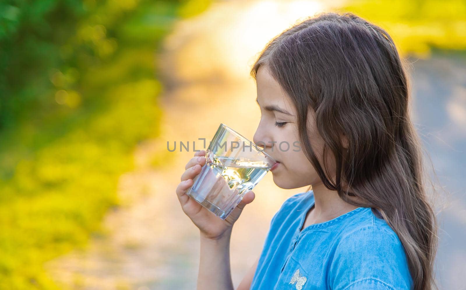 The child drinks water from a glass. Selective focus. by yanadjana