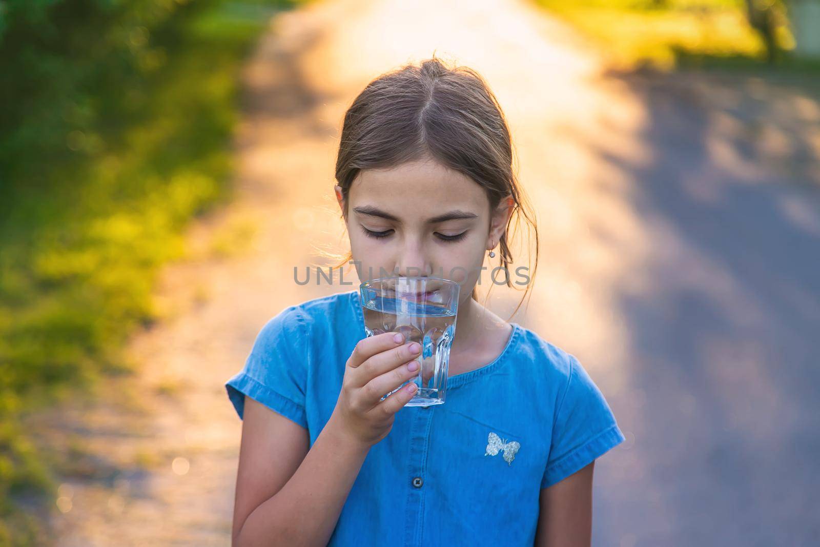 The child drinks water from a glass. Selective focus. by yanadjana