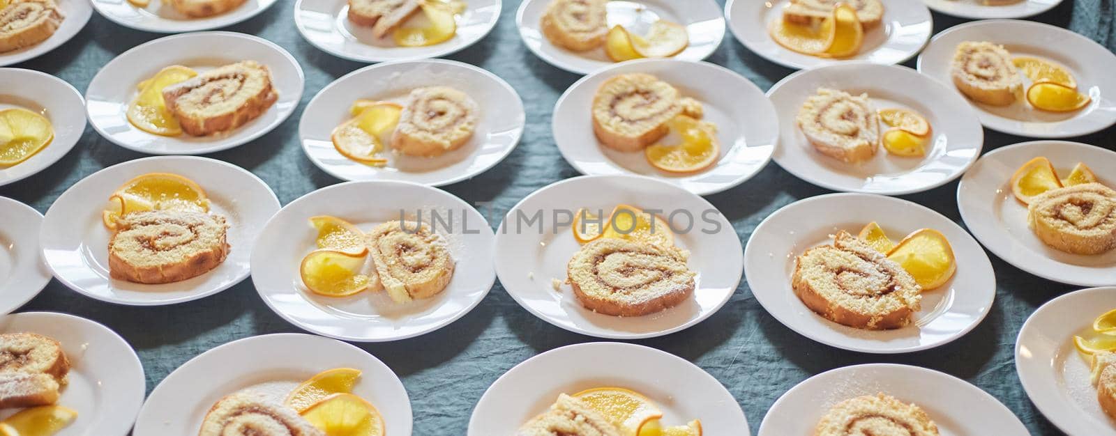 Sponge rolls with jam and a slice of orange on white plates. background. Banner by driver-s