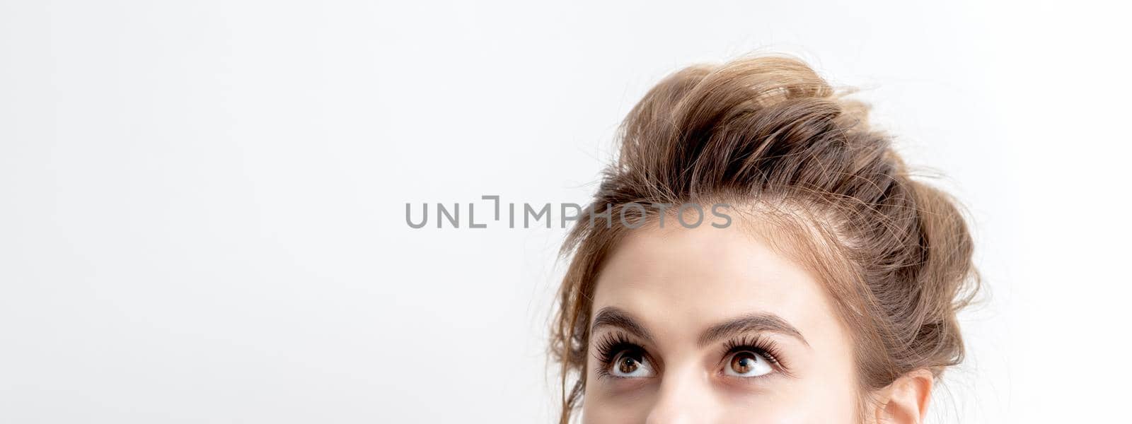 Young caucasian woman looking up on white background. Half face of woman looking upwards, copy space