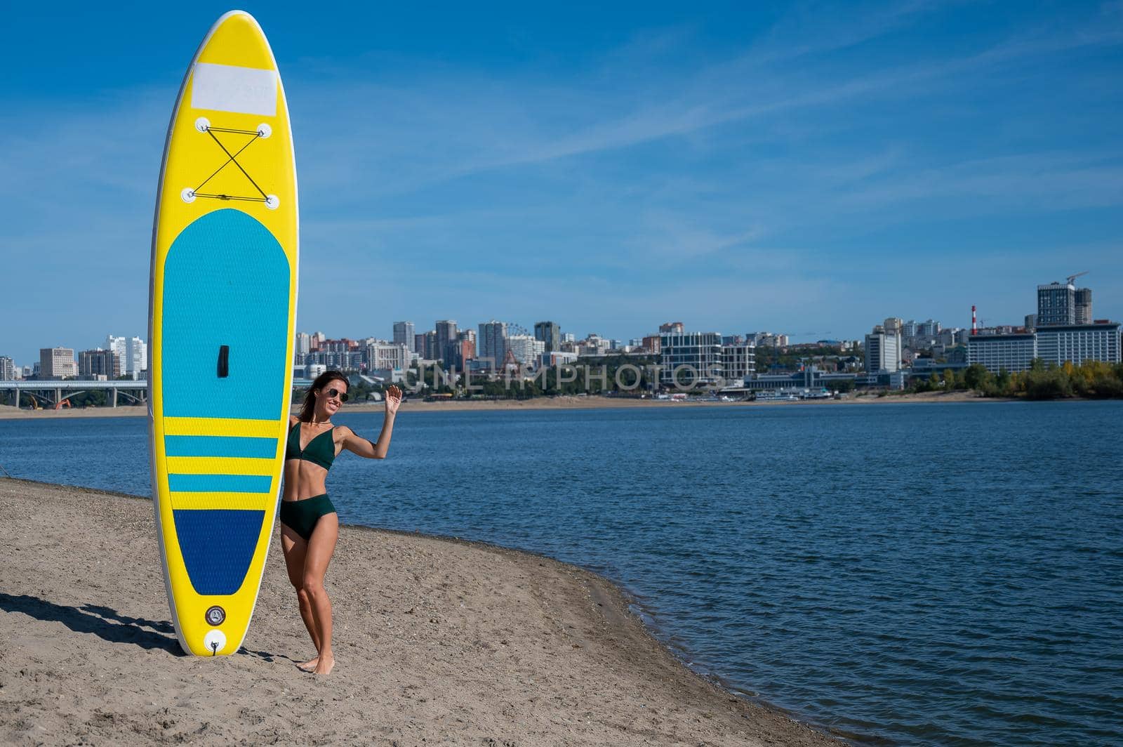 Caucasian woman walks along the beach and carries a sup board on the river in the city. Summer sport. by mrwed54