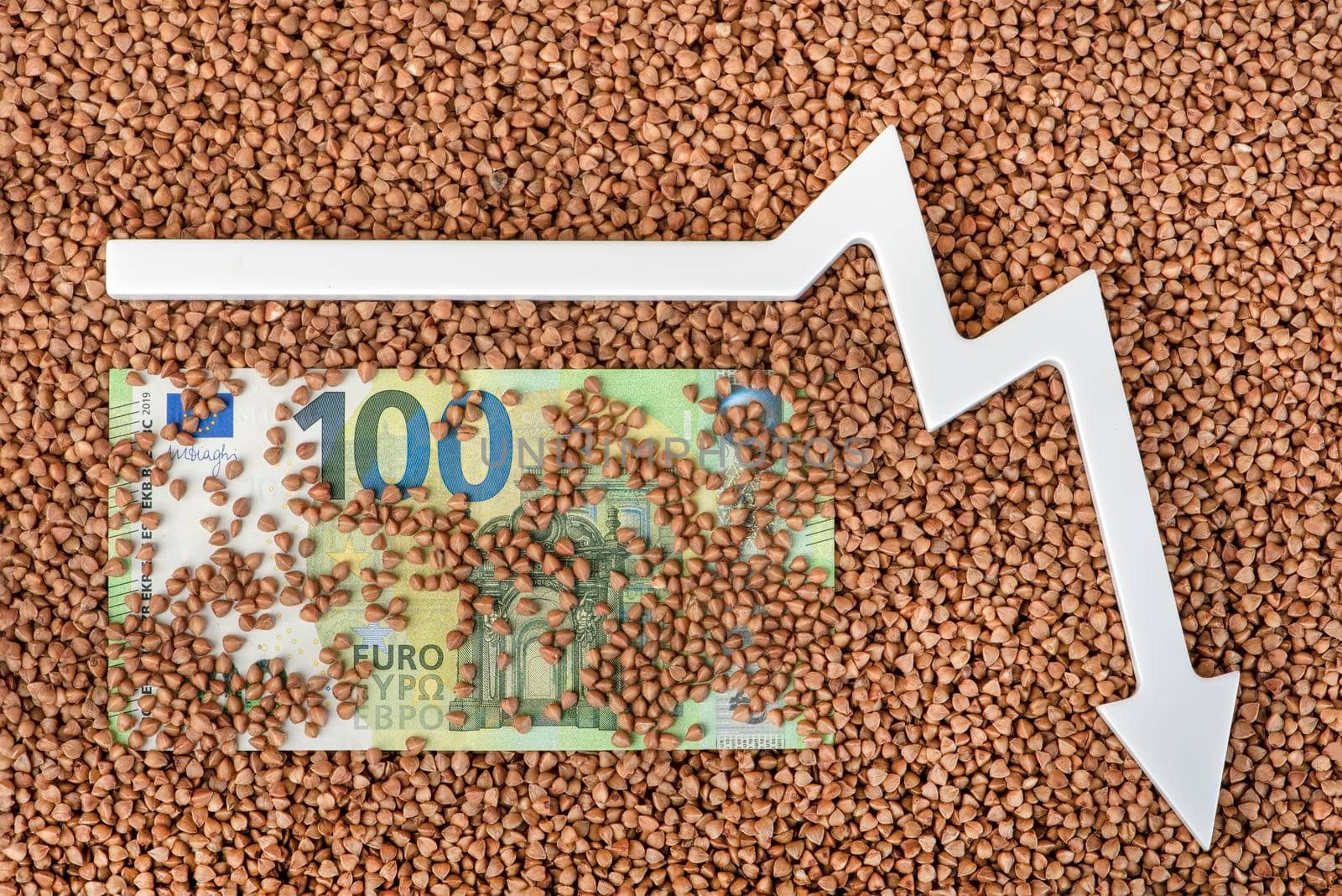 Buckwheat prices. World food crisis. Financial derivatives market. One hundred euro bill in buckwheat and the arrow of the graph is pointing down