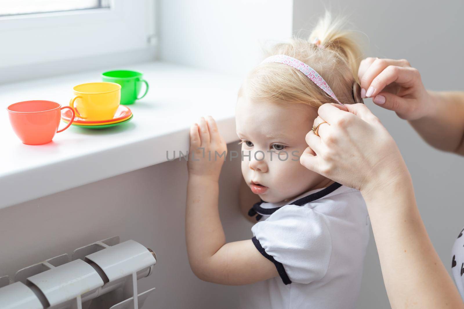 Mother fixing her daughter's cochlear implant hearing aid - deafness and diversity concept. Innovative technologies in treatment deafness