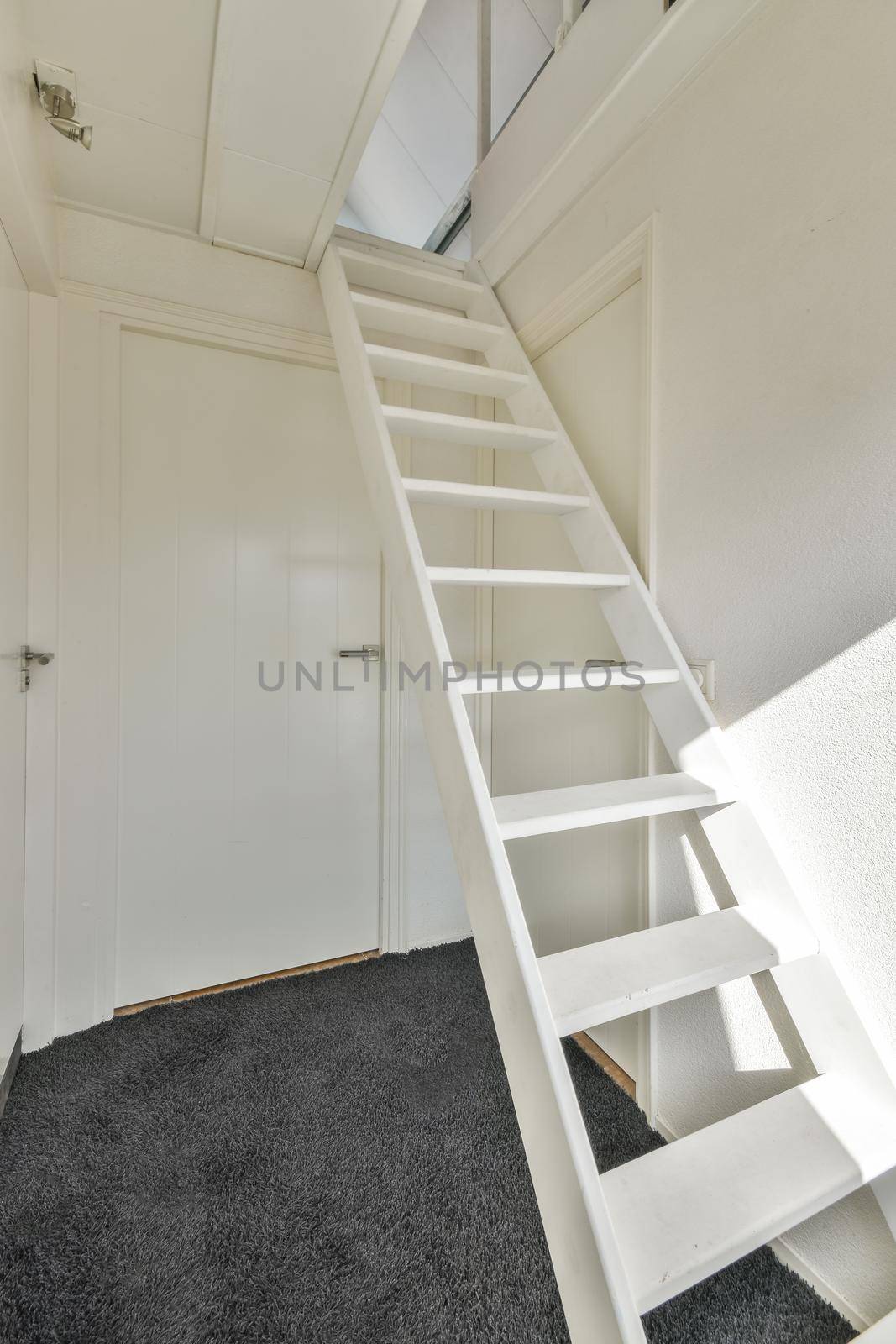 A simple minimalist room with a white staircase to the attic and a stylish carpet