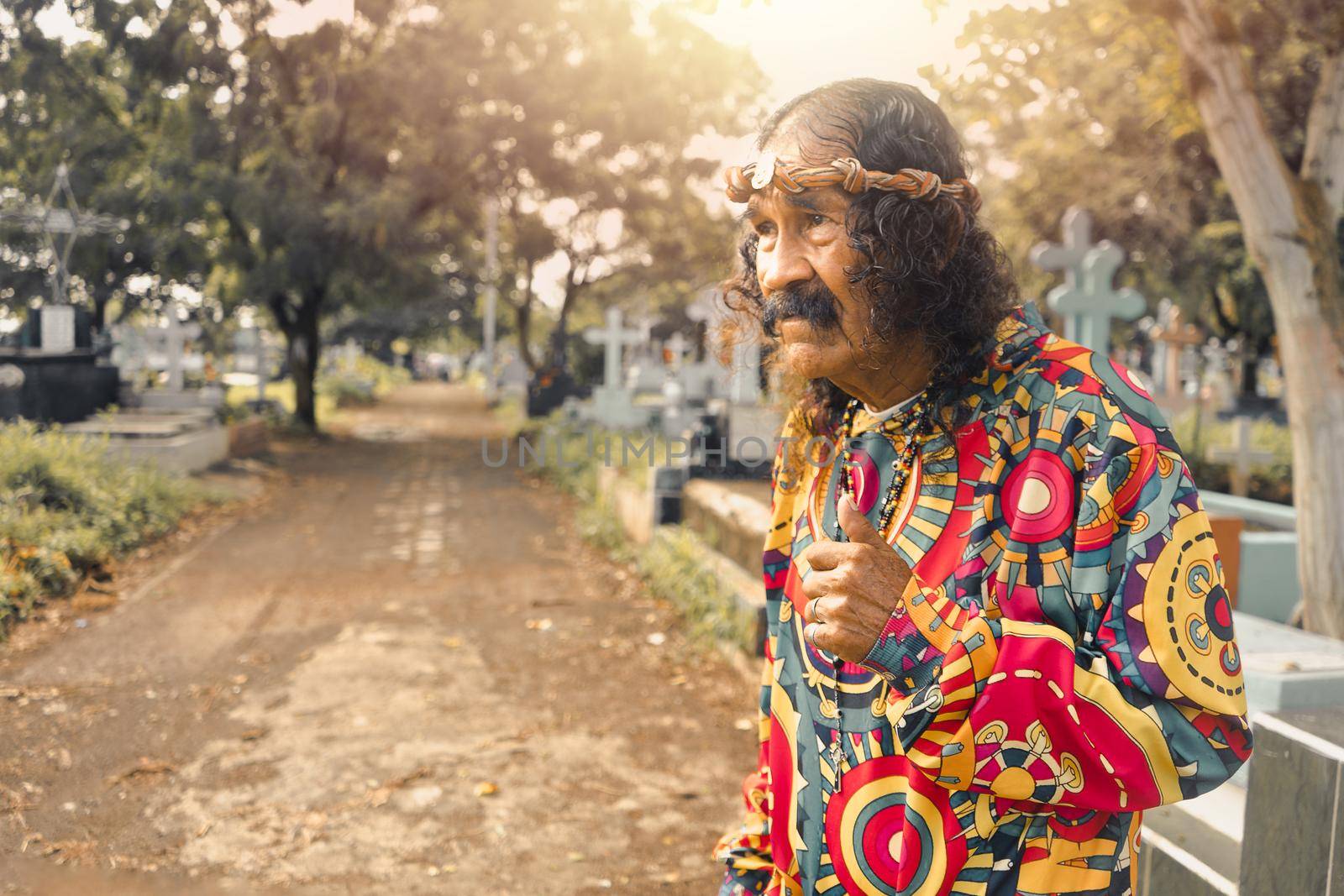 Latin old man dressed as Jesus Christ with psychedelic clothes in a cemetery in Managua Nicaragua