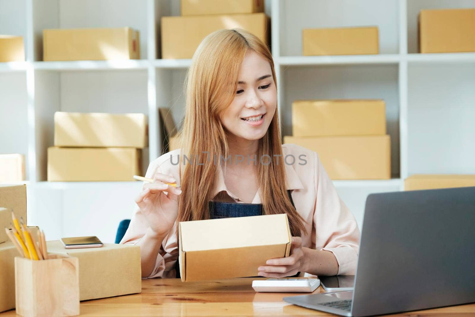 Online small business owner writing address on parcel box for delivery to customer, shipping and logistic, merchant online and seller, business owner or SME, online shopping.