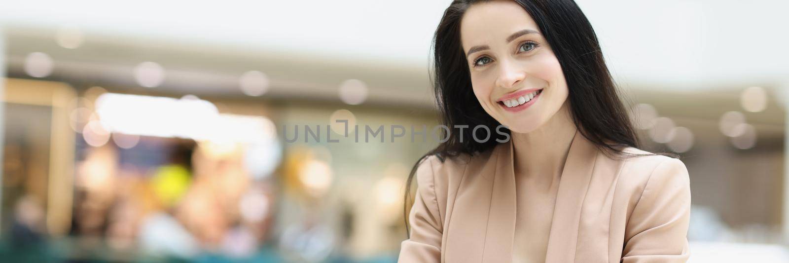 Portrait of beautiful young woman waiting for her date in cafe in mall. Smiling lady using smartphone to kill some time. Meeting, waiting, boring concept