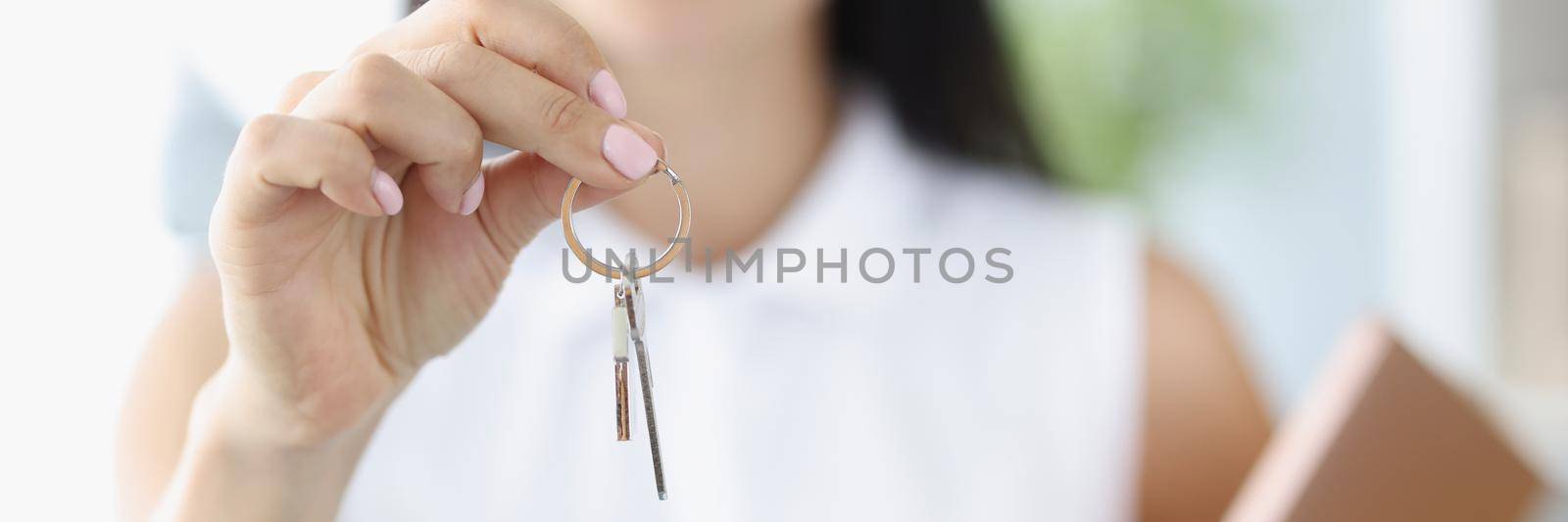 Close-up of agent or realtor holding key to new landlord or tenant or rental. Bank approved and signed purchase agreement. Real estate, mortgage concept