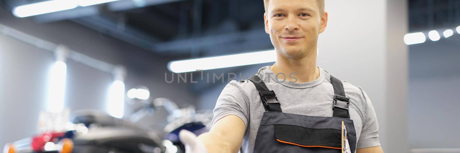Portrait of maintenance service worker willing to shake clients hand after good job. Car specialist work on maintenance station. Handshake, fixed concept