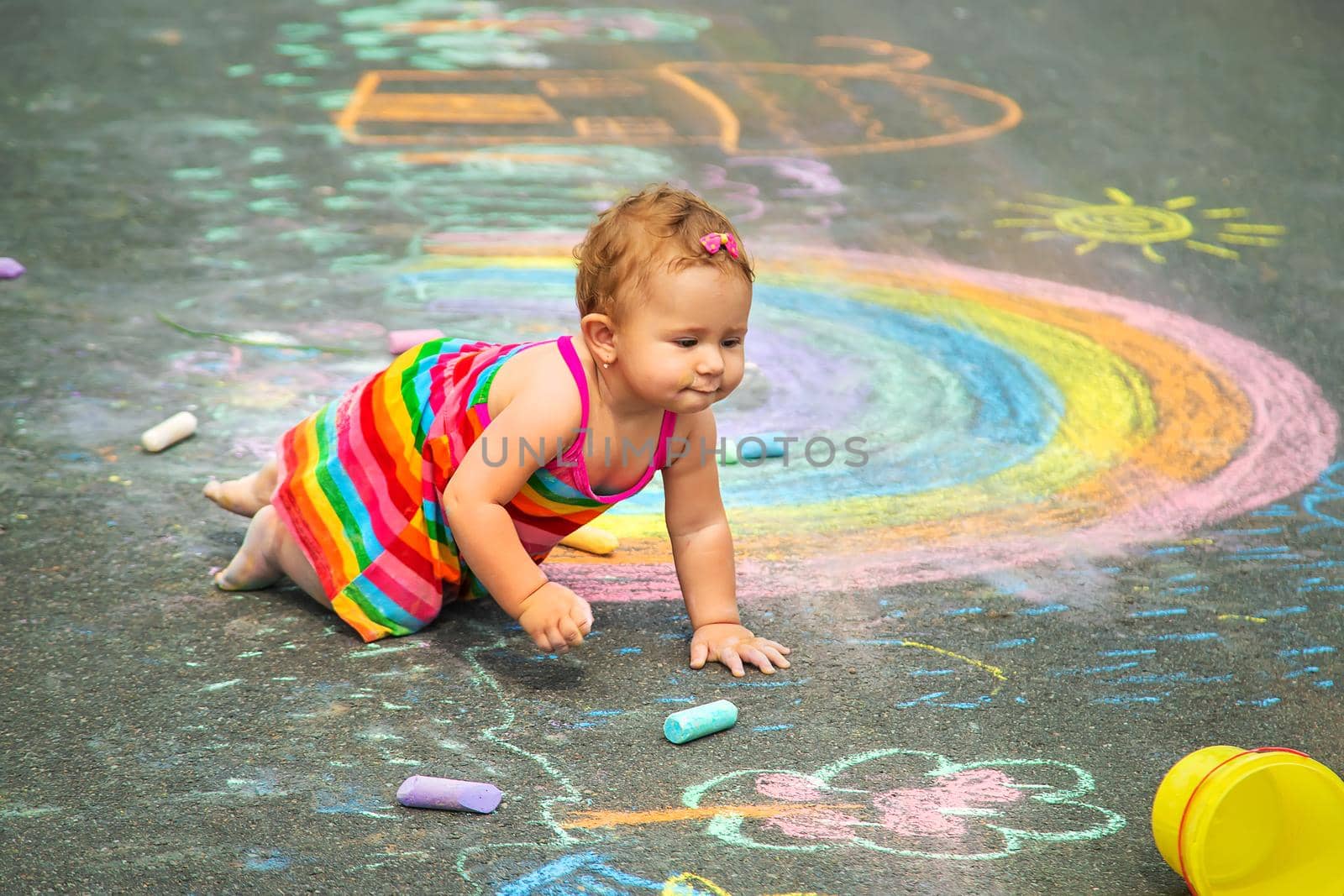 The child draws with chalk on the asphalt. Selective focus. Kid.