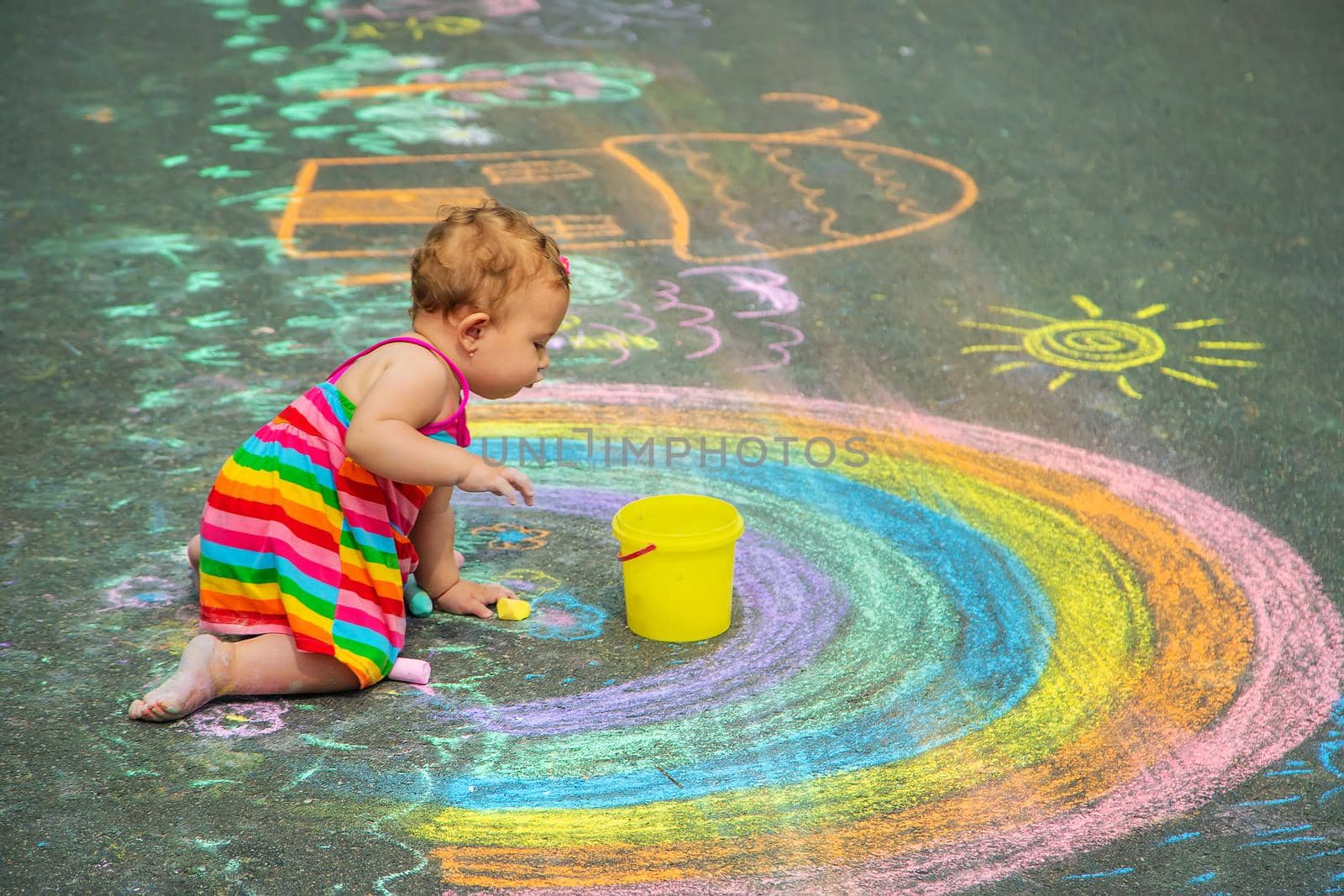 The child draws with chalk on the asphalt. Selective focus. Kid.