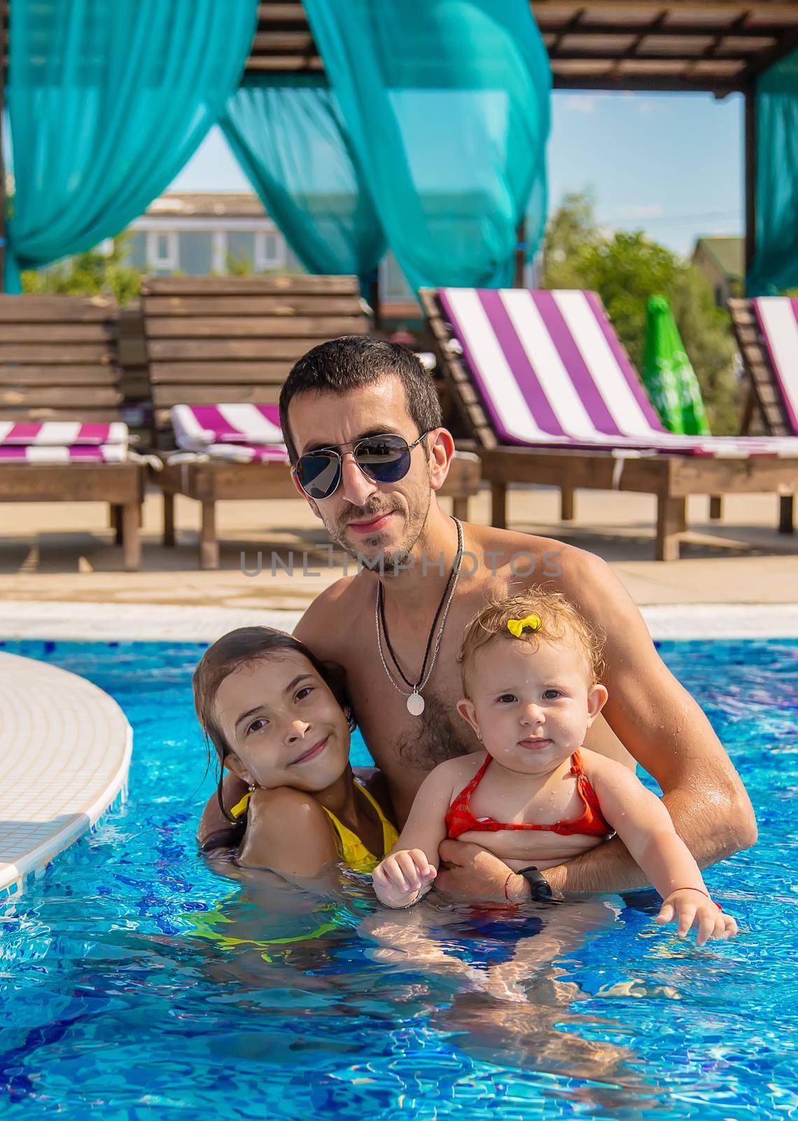 Father with daughters in the pool. Selective focus. Child.