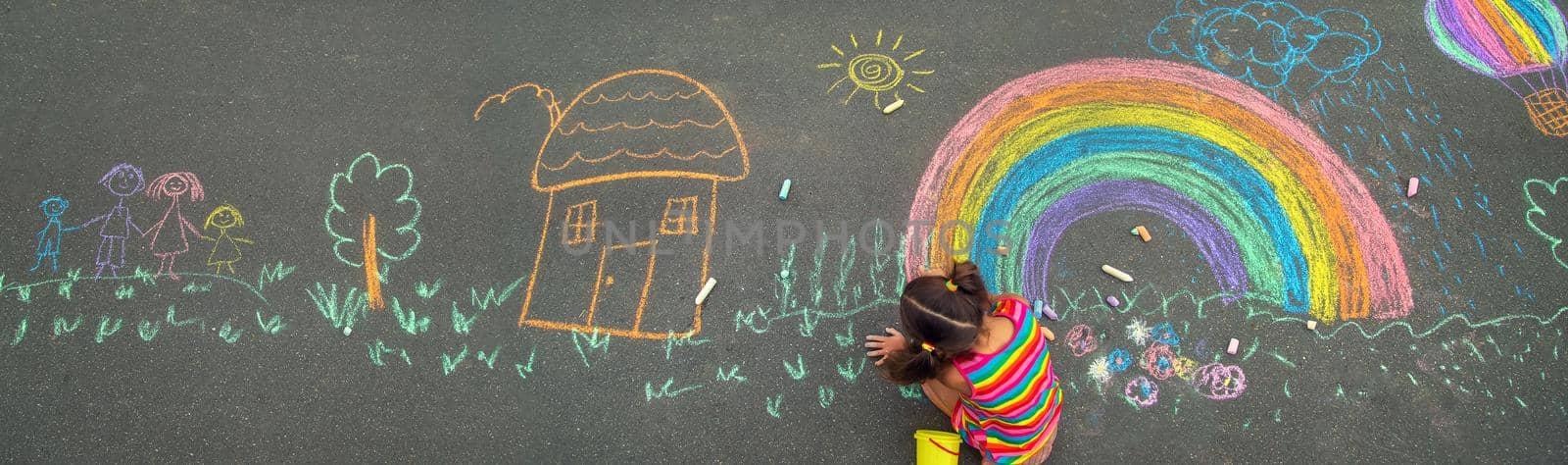 The child draws with chalk on the asphalt. Selective focus. by yanadjana