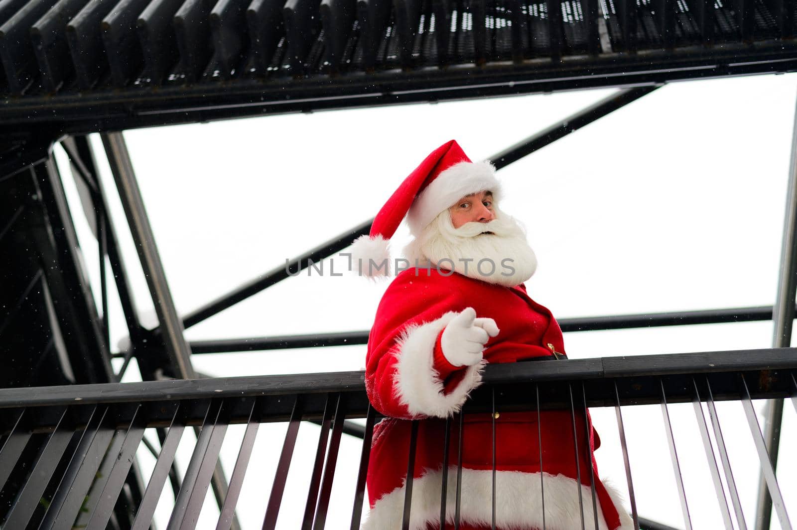 Santa claus looks down from the stairs and wishes a merry christmas outdoors by mrwed54