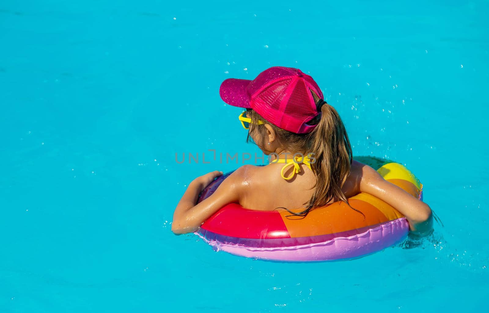 The child swims in the pool in a circle. Selective focus. Kid.