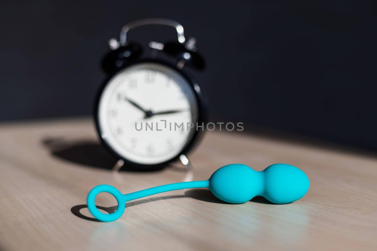 Alarm clock and vibrator on the table. Time for training intimate muscles. Vaginal balls strengthen the pelvic floor muscles for powerful orgasms