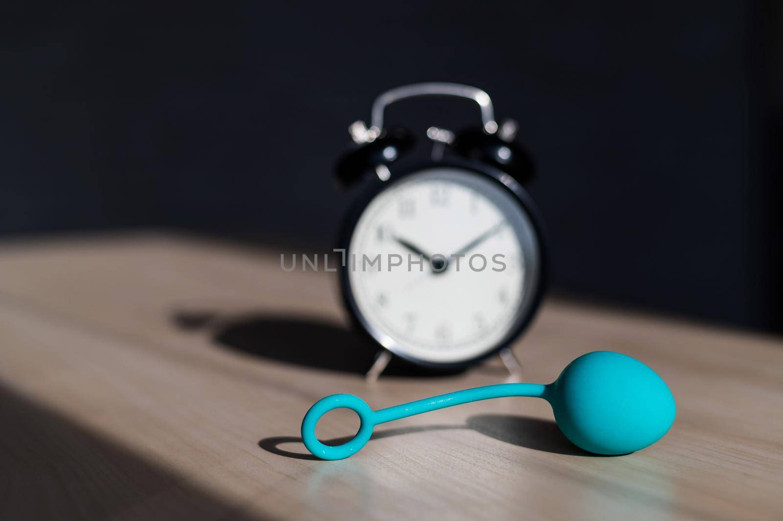 Alarm clock and vibrator on the table. Time for training intimate muscles. Vaginal balls strengthen the pelvic floor muscles for powerful orgasms