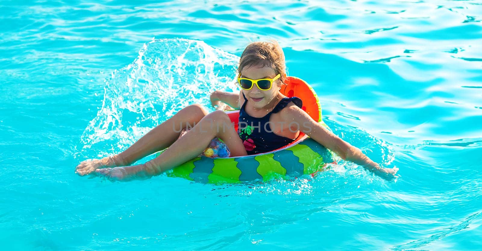 A child in a circle swims in the pool. Selective focus. Kid.