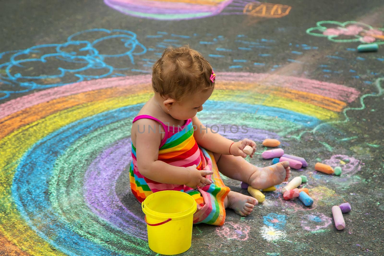 The child draws with chalk on the asphalt. Selective focus. Kid.