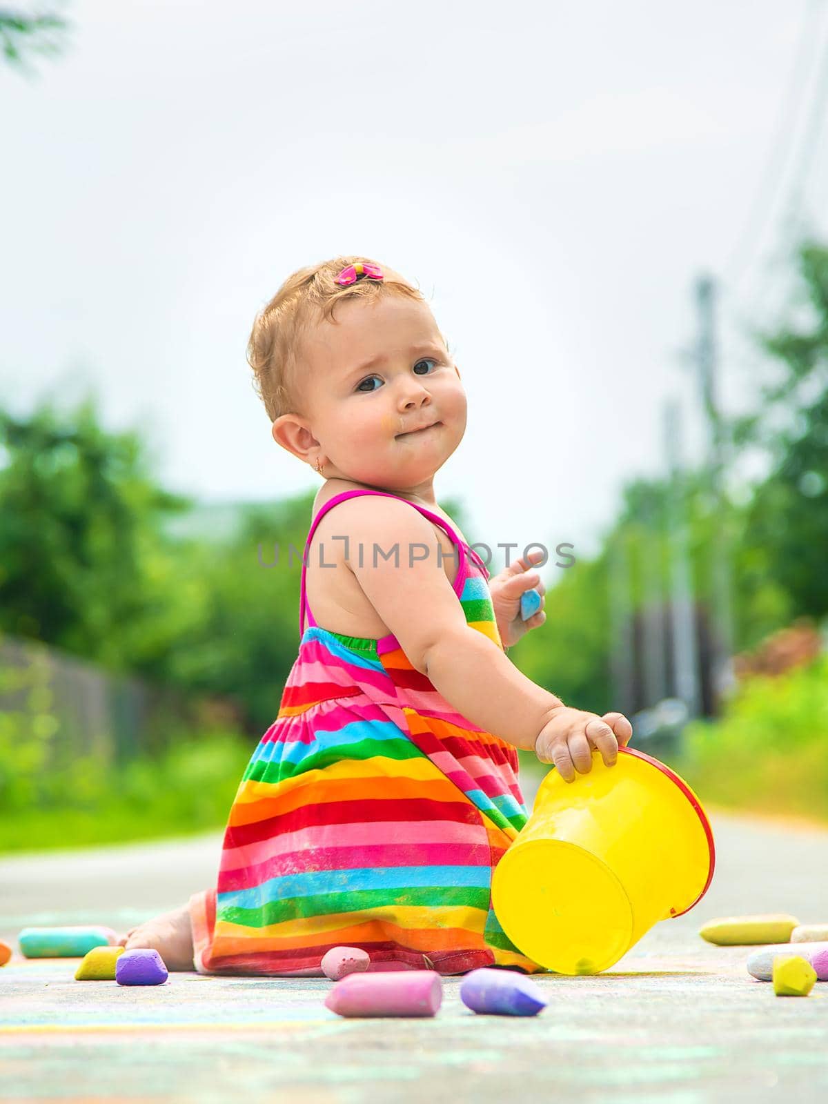 The child draws with chalk on the asphalt. Selective focus. Kid.