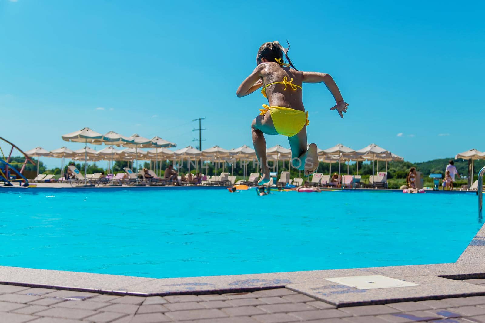 The child jumps into the pool. Selective focus. Kid.