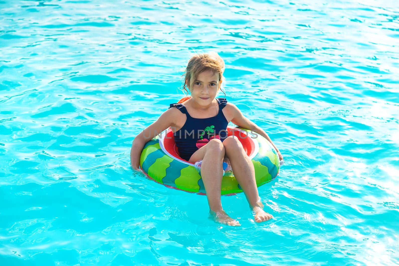 A child in a circle swims in the pool. Selective focus. Kid.