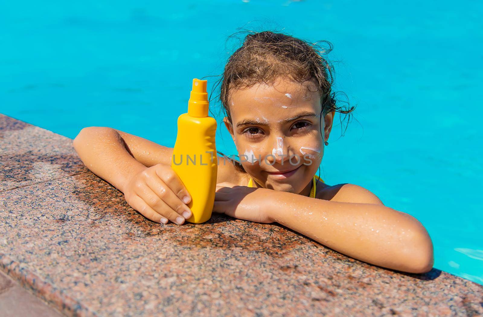 Sunscreen near the pool on the face of the child. Selective focus. Kid.