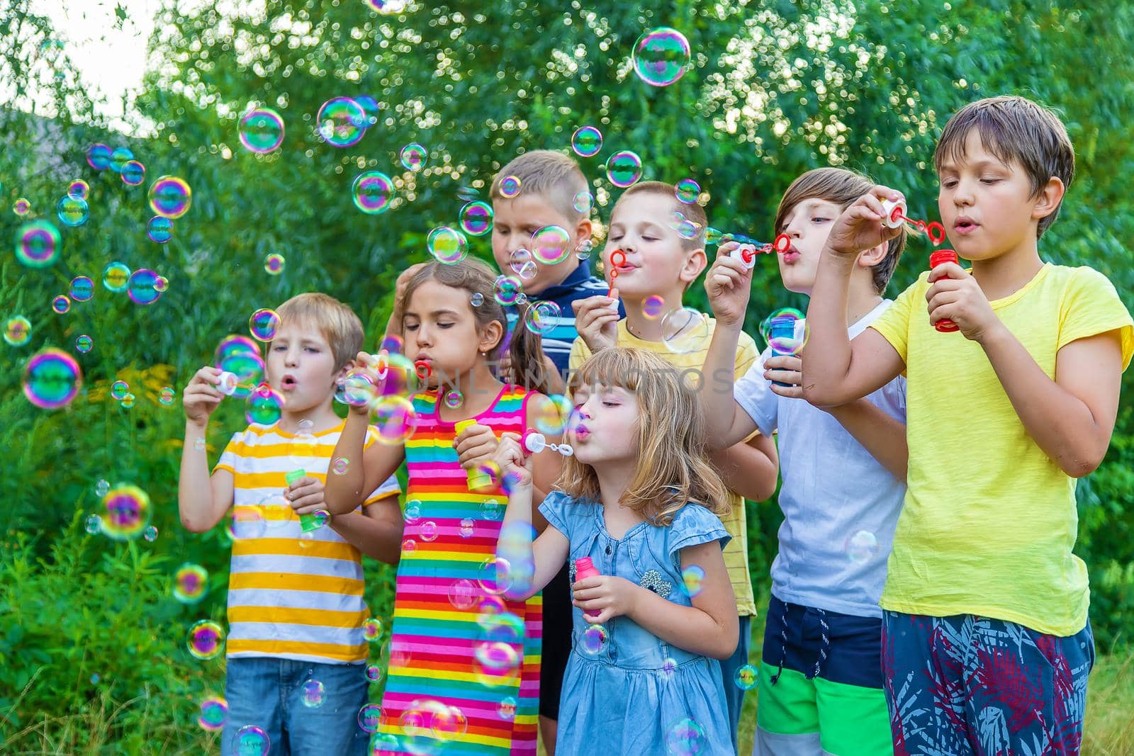 Children blow bubbles in the street. Selective focus. by yanadjana