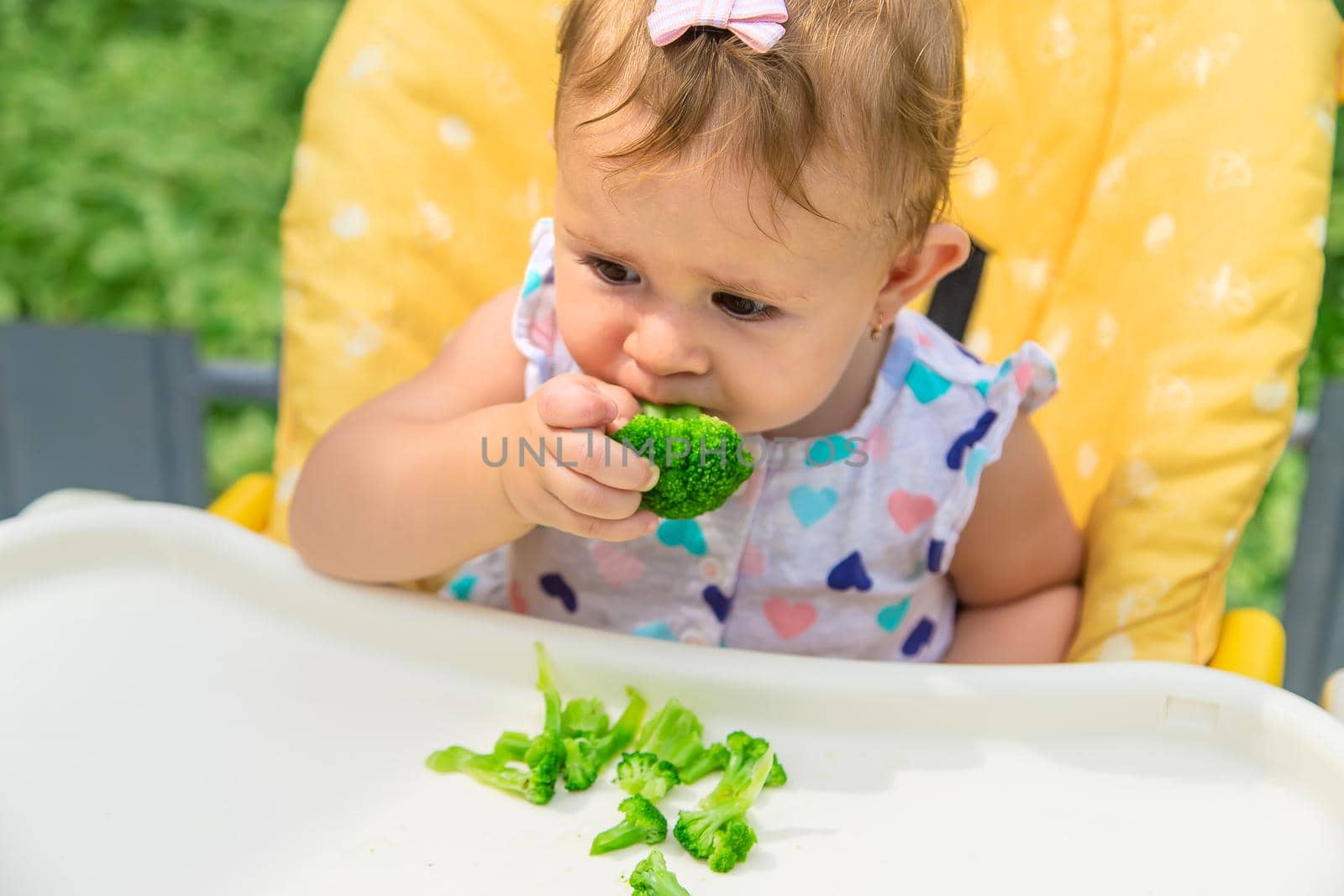 Baby eats pieces of broccoli vegetables. Selective focus. Child.
