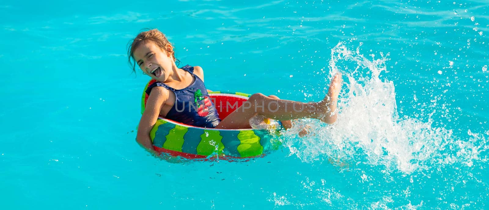 A child in a circle swims in the pool. Selective focus. Kid.