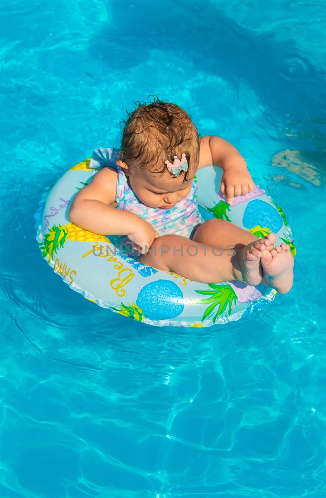 Baby in the pool swims in a circle. Selective focus. by yanadjana