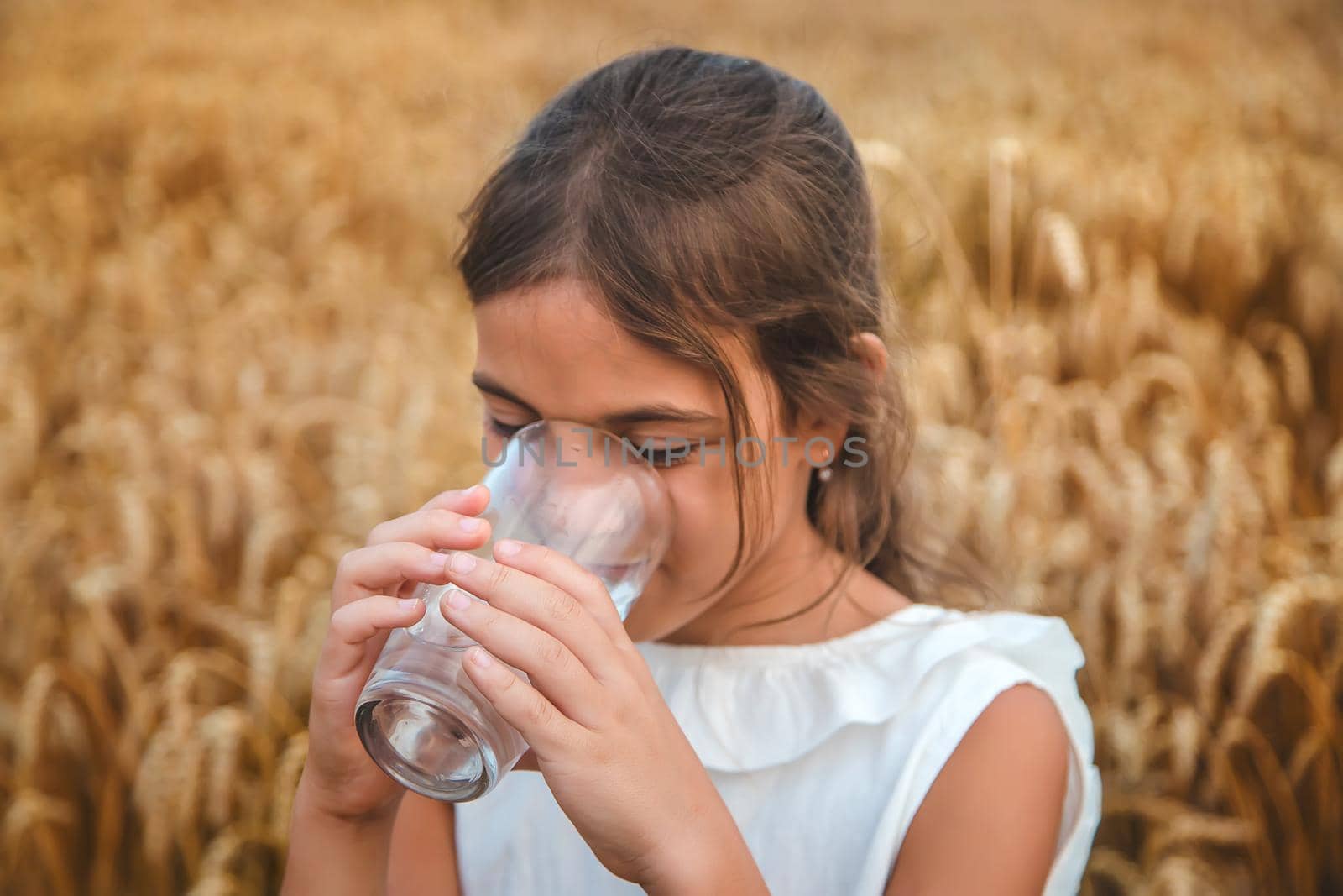 The child drinks water from a glass. Selective focus. Kid.
