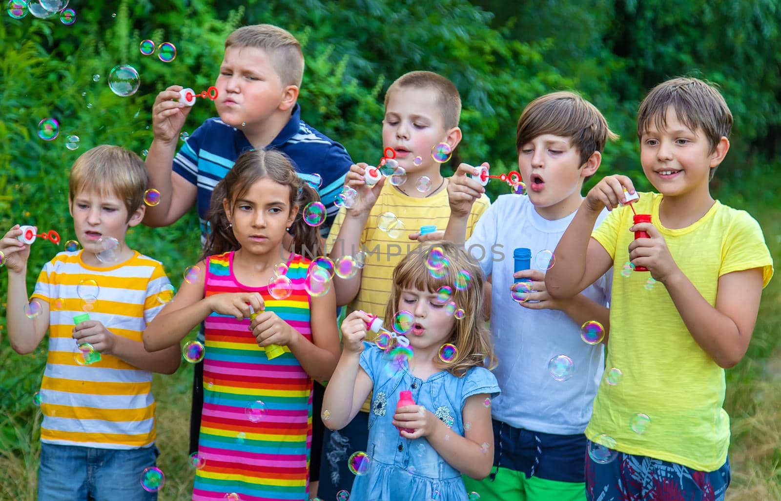 Children blow bubbles in the street. Selective focus. by yanadjana