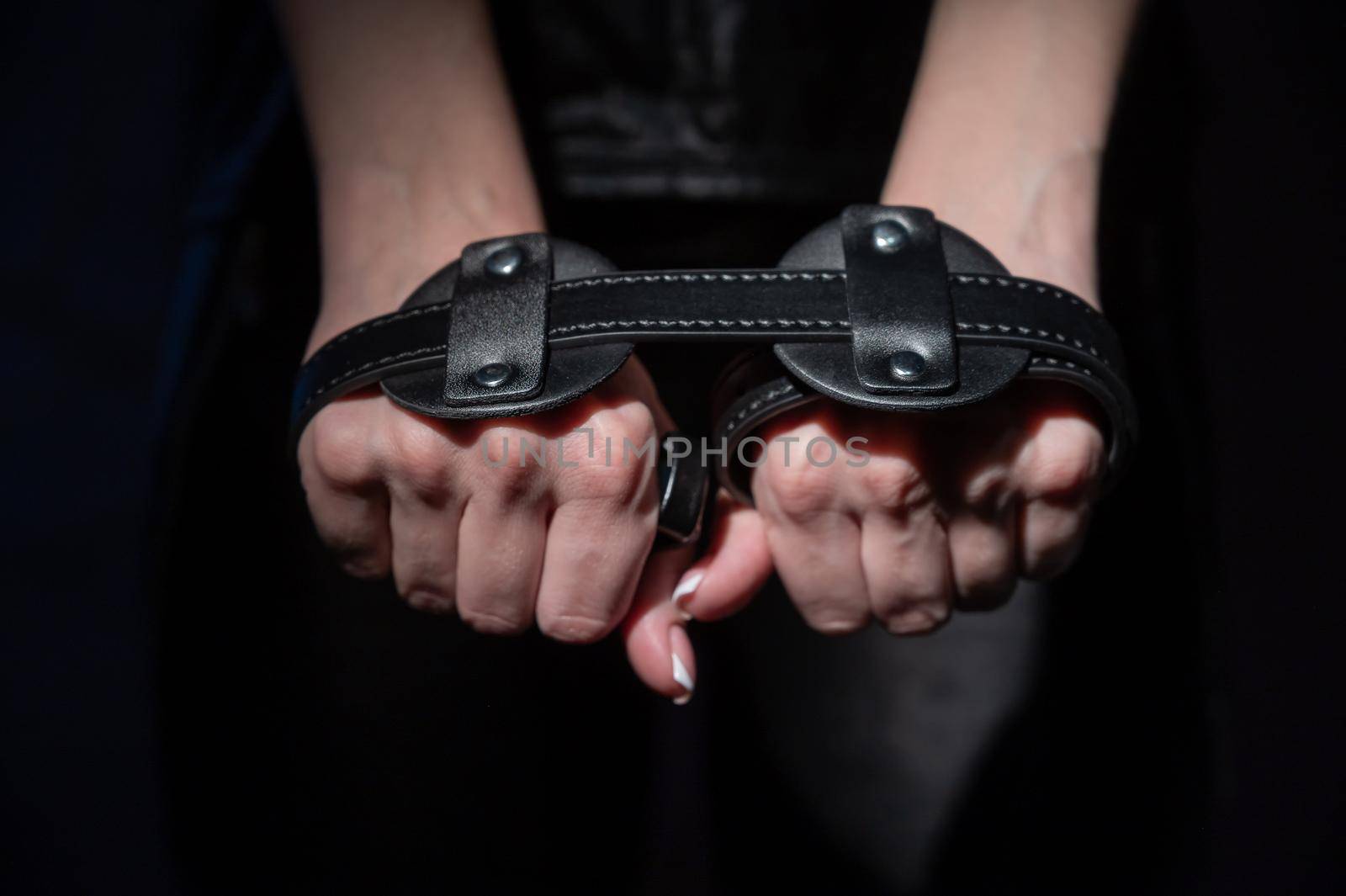 Close-up leather blindfolds in female hands. Unrecognizable woman holds bdsm equipment in the dark. Sexual role-playing games for adults. Humility and dominance