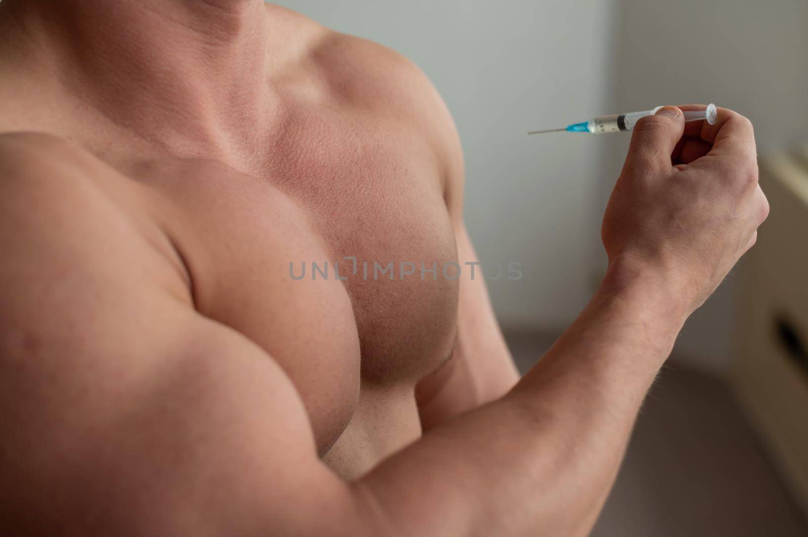 Close-up of a naked male torso. Unrecognizable shirtless bodybuilder man puts himself an injection of testosterone. Faceless athlete takes dope. by mrwed54
