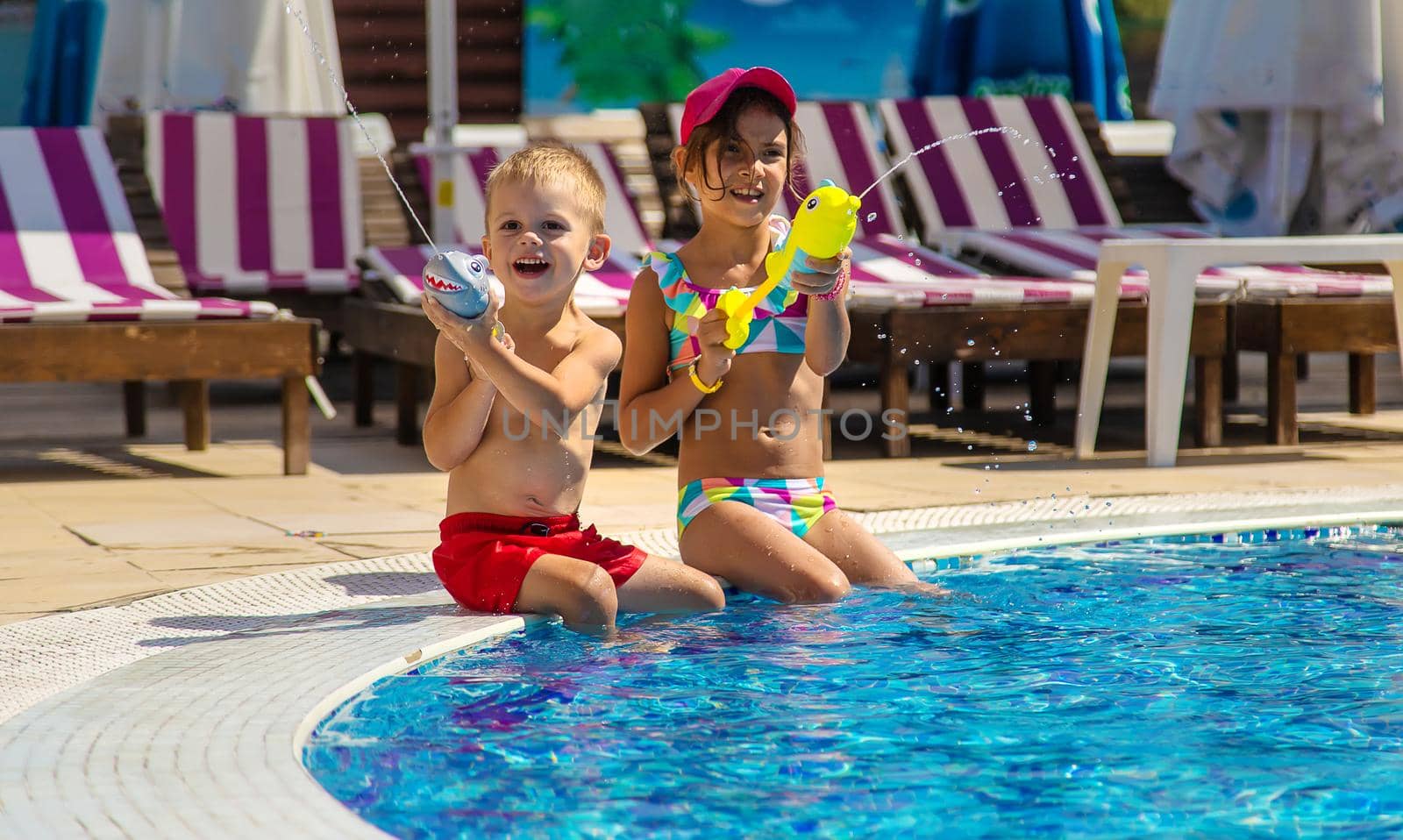 Children play with water pistols in the pool. Selective focus. Water.