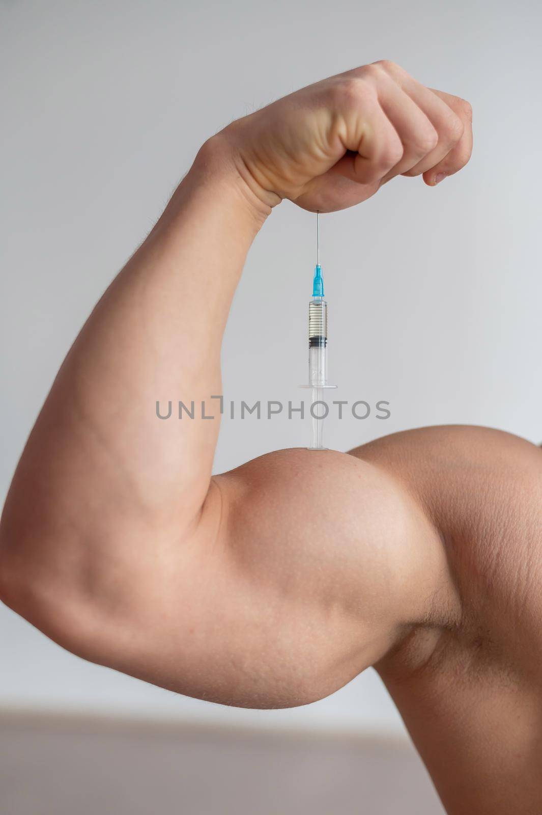 Close-up of male biceps. Unrecognizable male bodybuilder puts himself an injection of testosterone. Faceless athlete takes growth hormone. Vertical . by mrwed54
