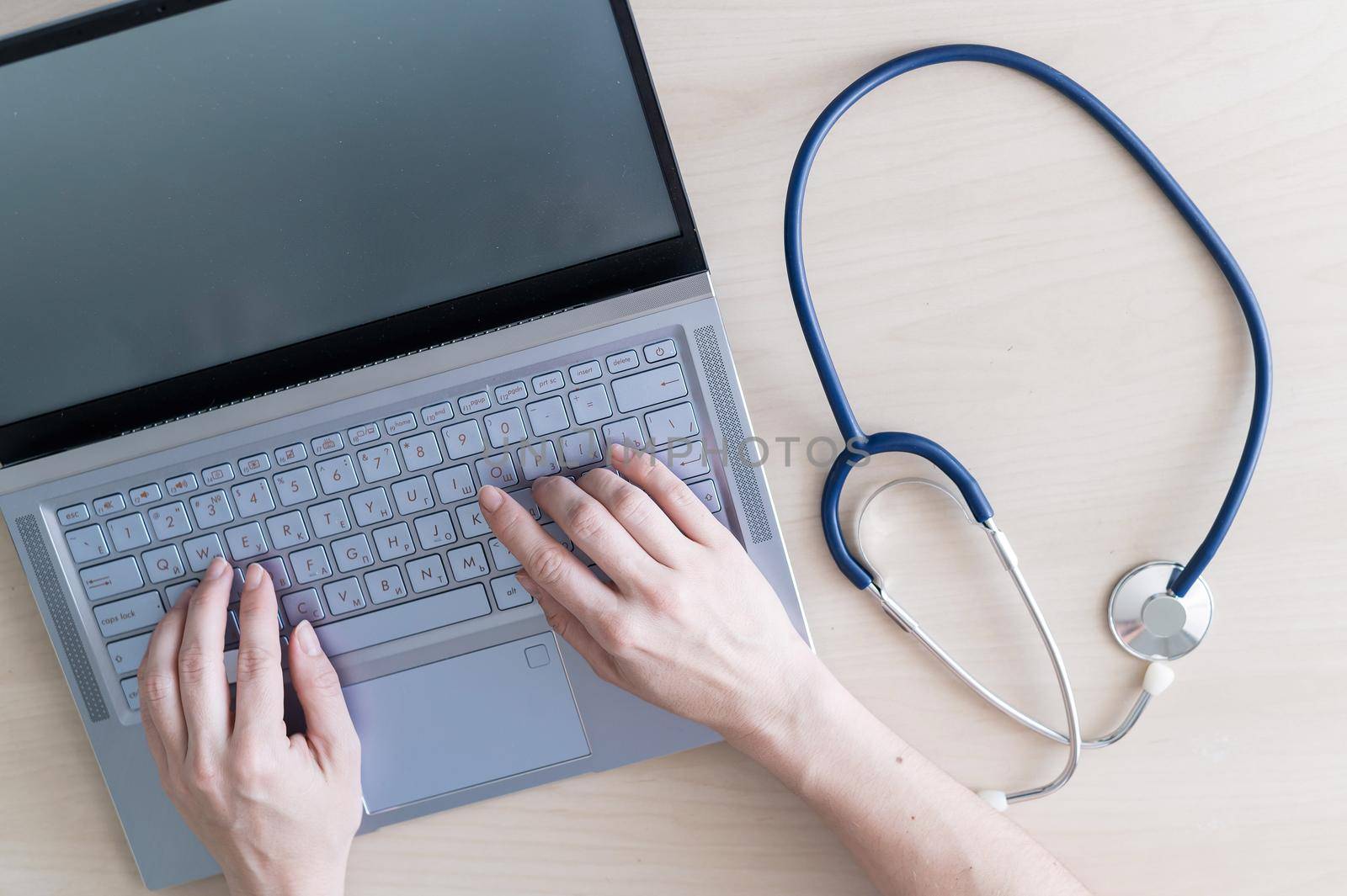 Top view of hands on the keyboard. Woman doctor at the desk typing on a laptop. A nurse fills out a patients electronic card. by mrwed54