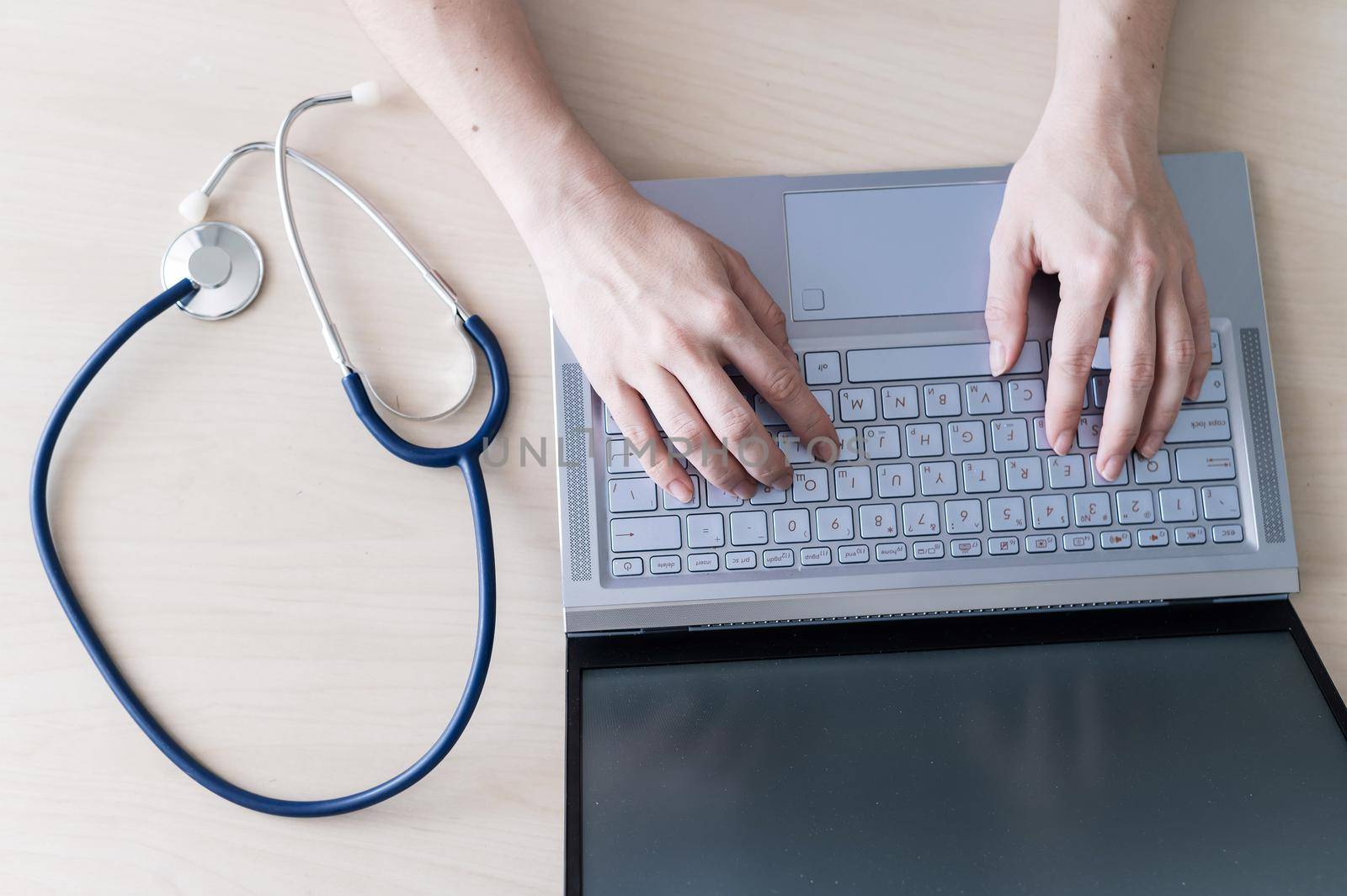 Top view of hands on the keyboard. Woman doctor at the desk typing on a laptop. A nurse fills out a patients electronic card. by mrwed54