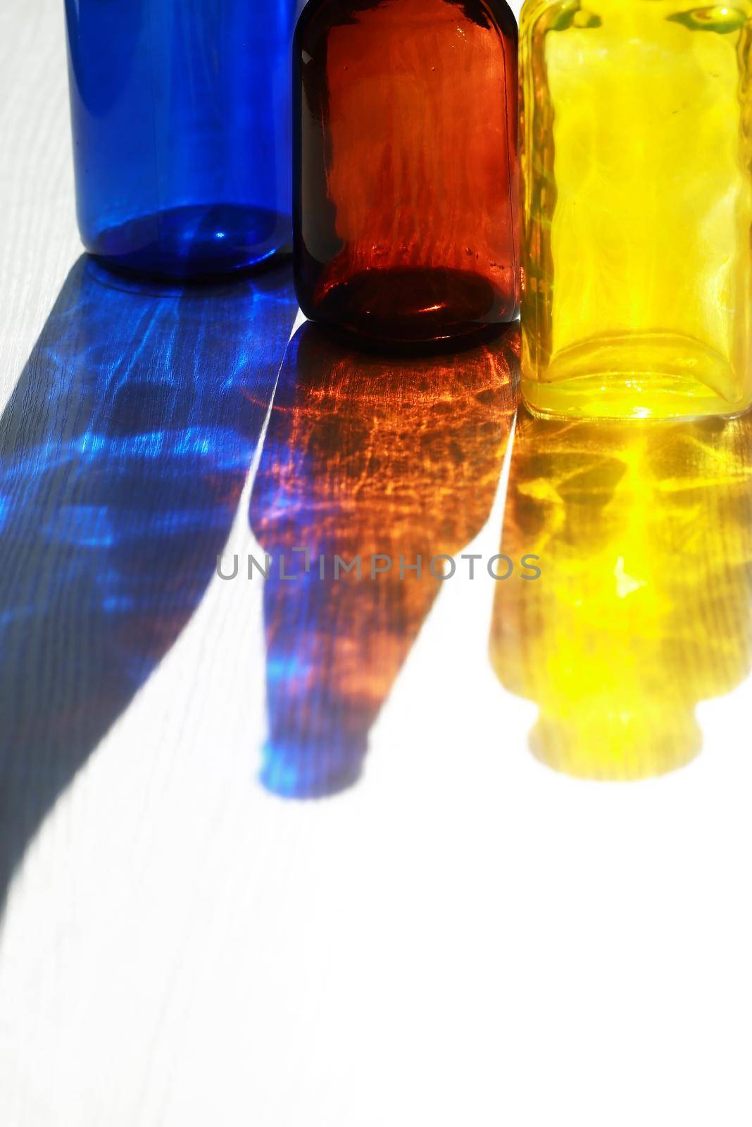 Set of empty multicolored glass bottles with nice shadow against sun light