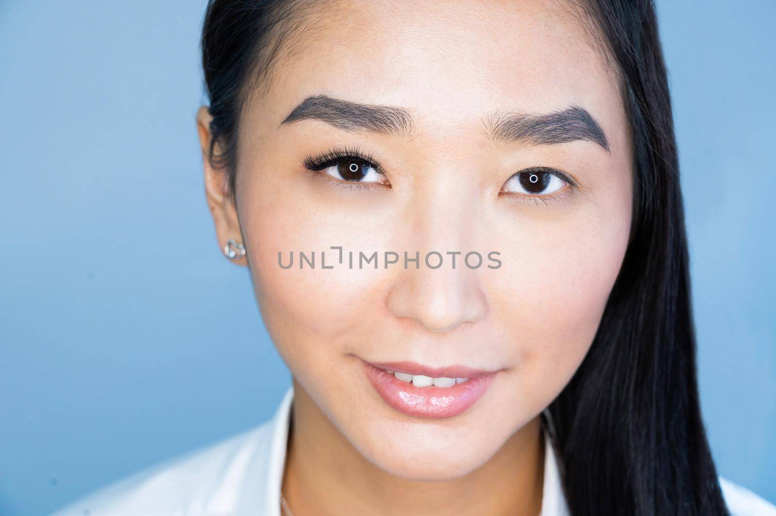 Portrait of a beautiful asian woman during eyelash extension procedure. Double eyelash volume before and after