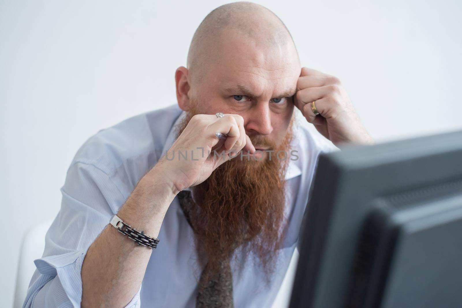 Problems for the office worker. A bald man in a white shirt sits at a desk with a computer and is stressed because of failure. A nervous breakdown