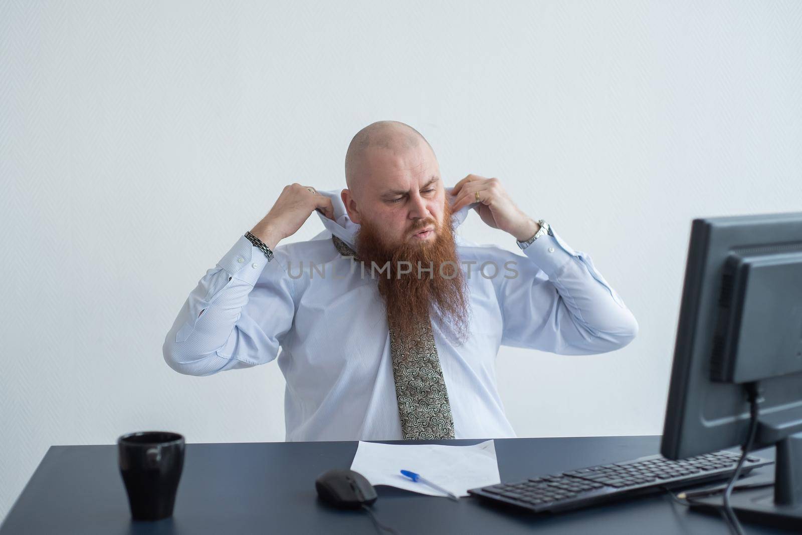 Problems for the office worker. A bald man in a white shirt sits at a desk with a computer and is stressed because of failure. A nervous breakdown