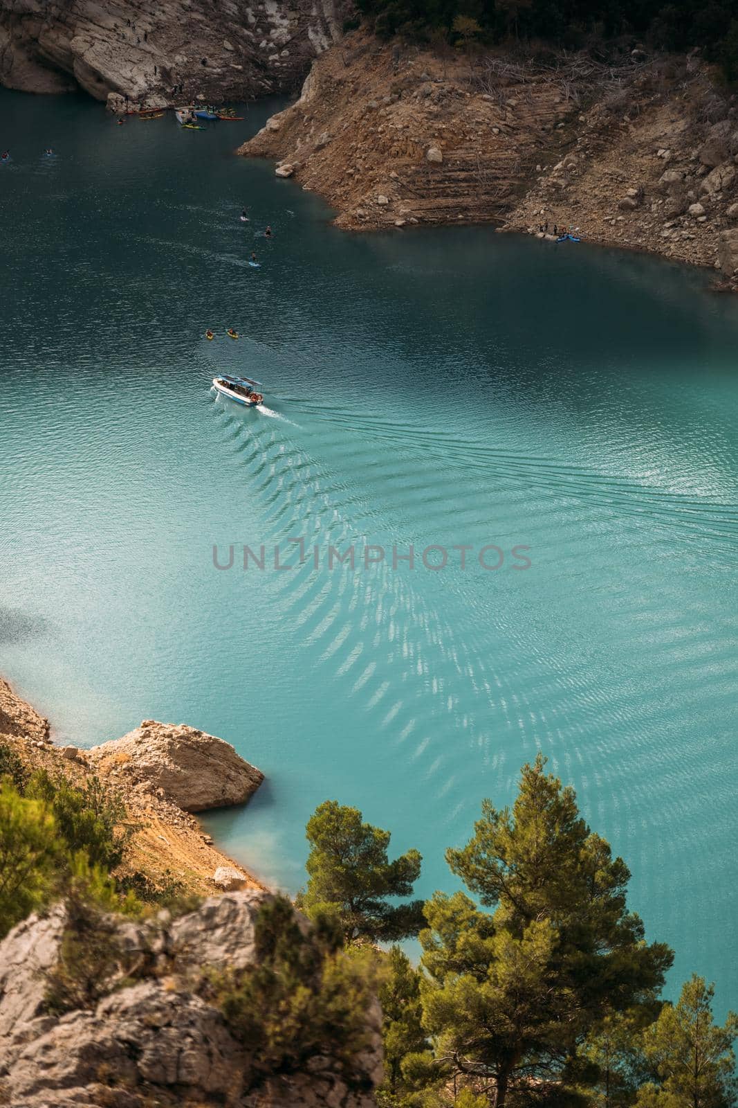 Boat floating and leaving a trail on the turquoise water surface. Summer vacation holidays. Congost de Mont Rebei, Catalonia, Spain.