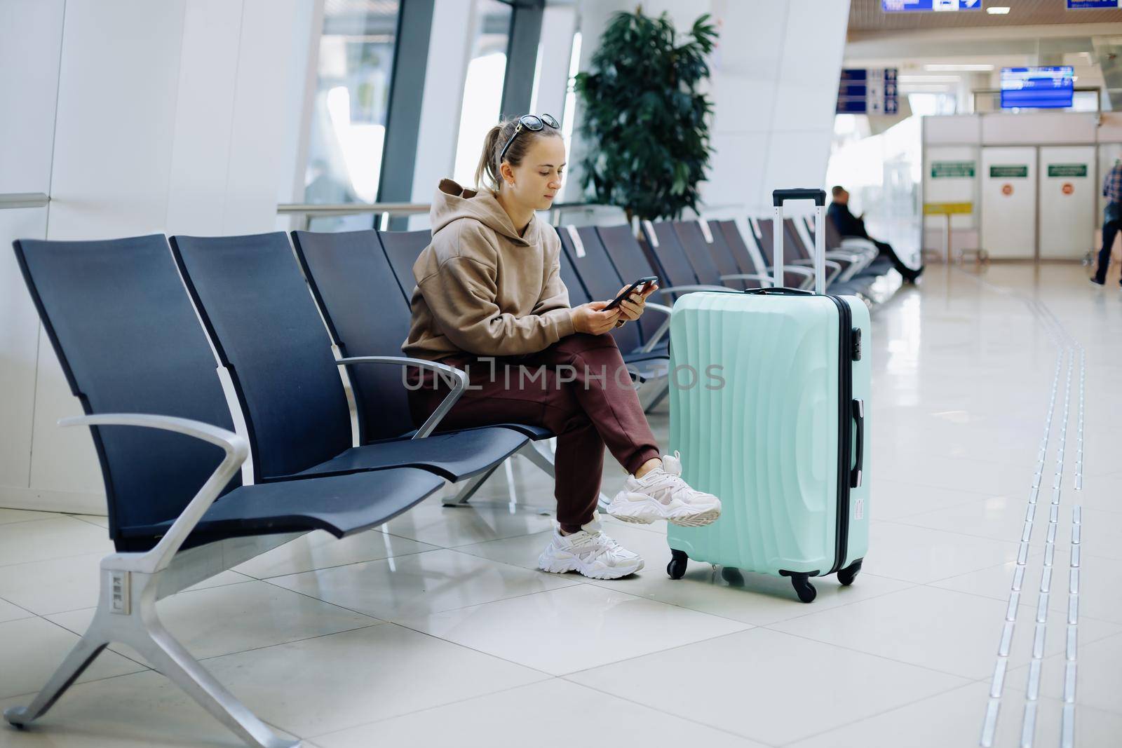 young woman using her smartphone at the airport . by SmartPhotoLab