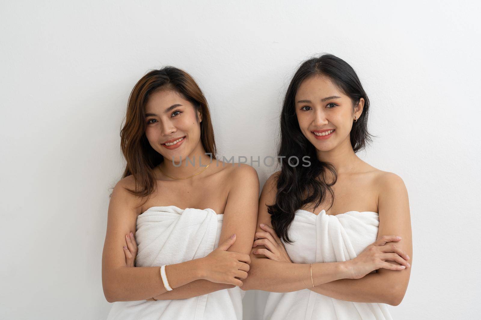 Portrait of Smiling young LGBT lesbian couple wearing a white towel standing and hugging each other affectionately together