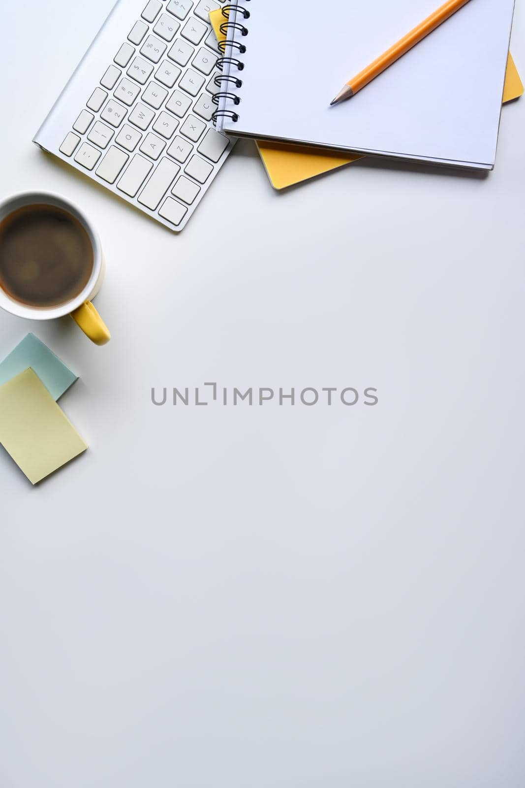 Flat lay, coffee cup, notebook and wireless keyboard on white table with copy space.